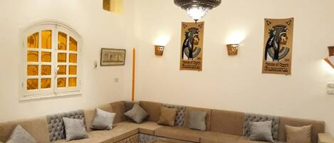 Una sala de estar con un sofá modular, una mesa de centro y adornos en la pared.