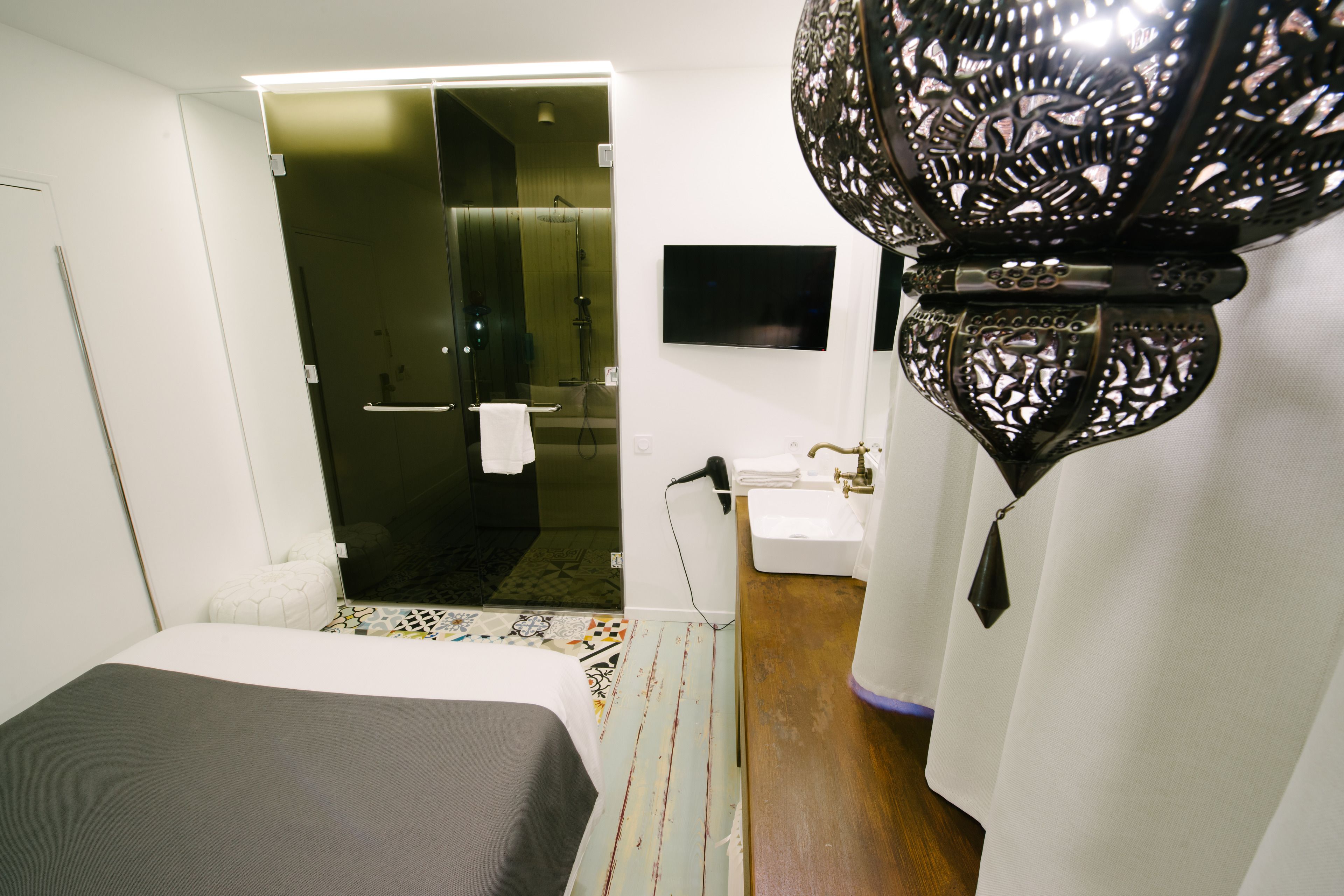 A hotel room with a bed, a bathroom with a shower, a sink, and a TV mounted on the wall.