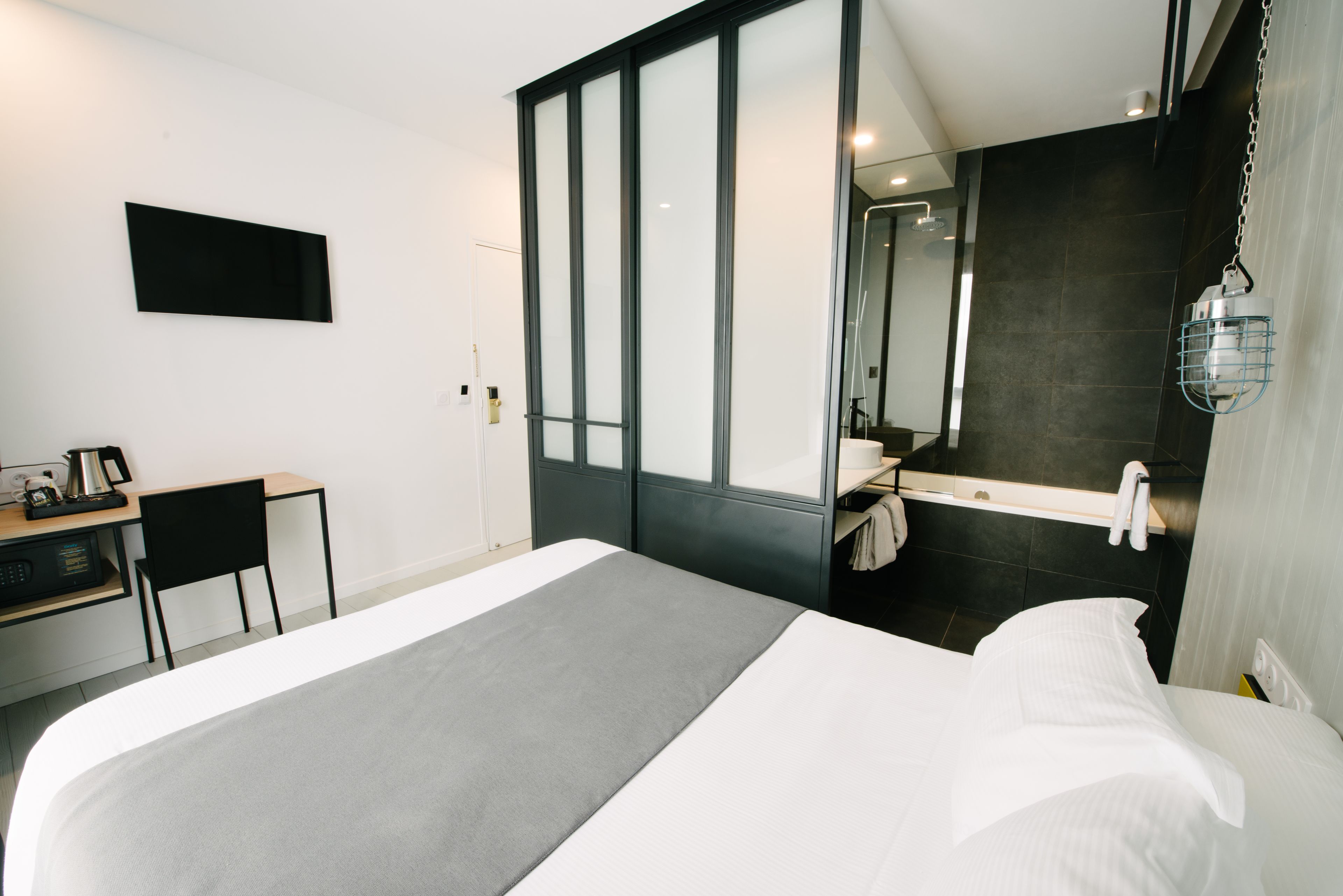 A modern hotel room with a bed, a desk, and a bathroom.