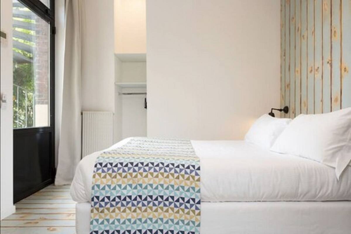 Un dormitorio con cama, ventana y radiador.