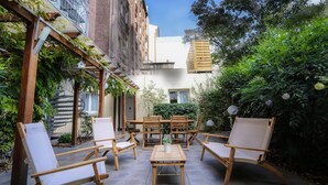 An outdoor patio with wooden furniture, a spiral staircase, and greenery. - Atypik Hôtel - Urban Style (Clichy)