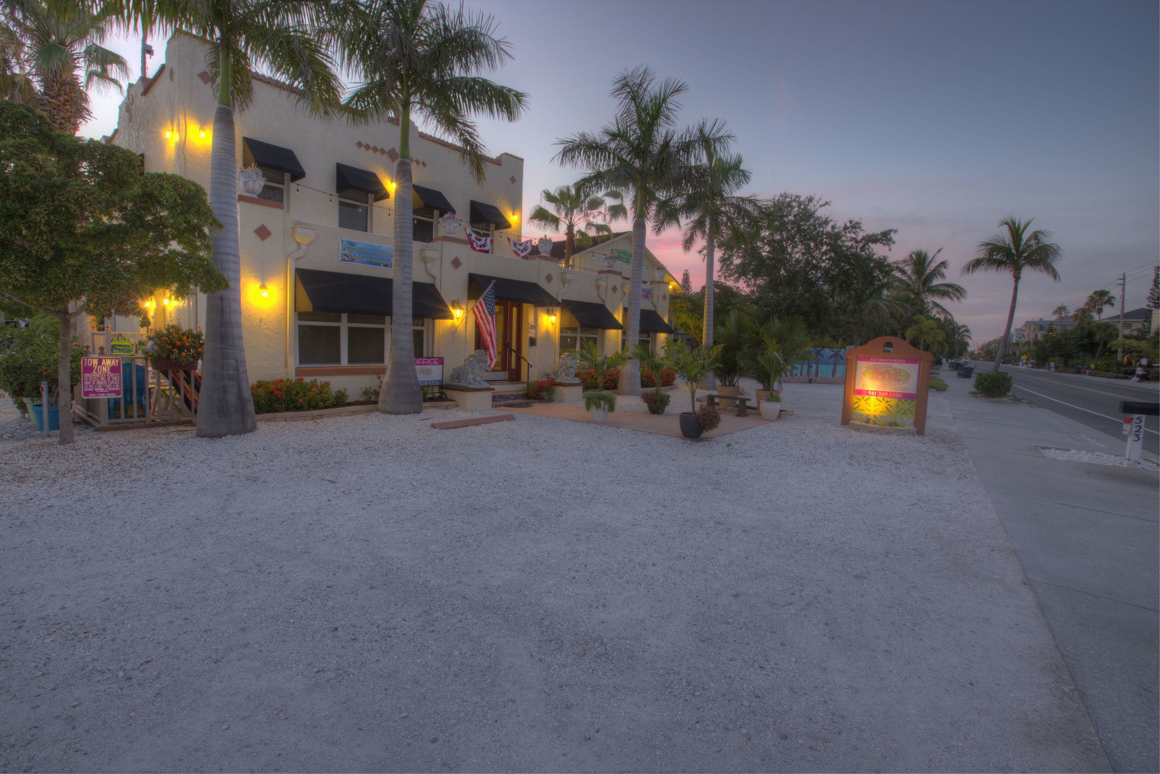 A hotel with a two-story structure, outdoor seating area, and palm trees.
