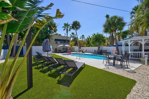 Un jardin avec une piscine, des chaises longues, une table avec des chaises et un gazebo.