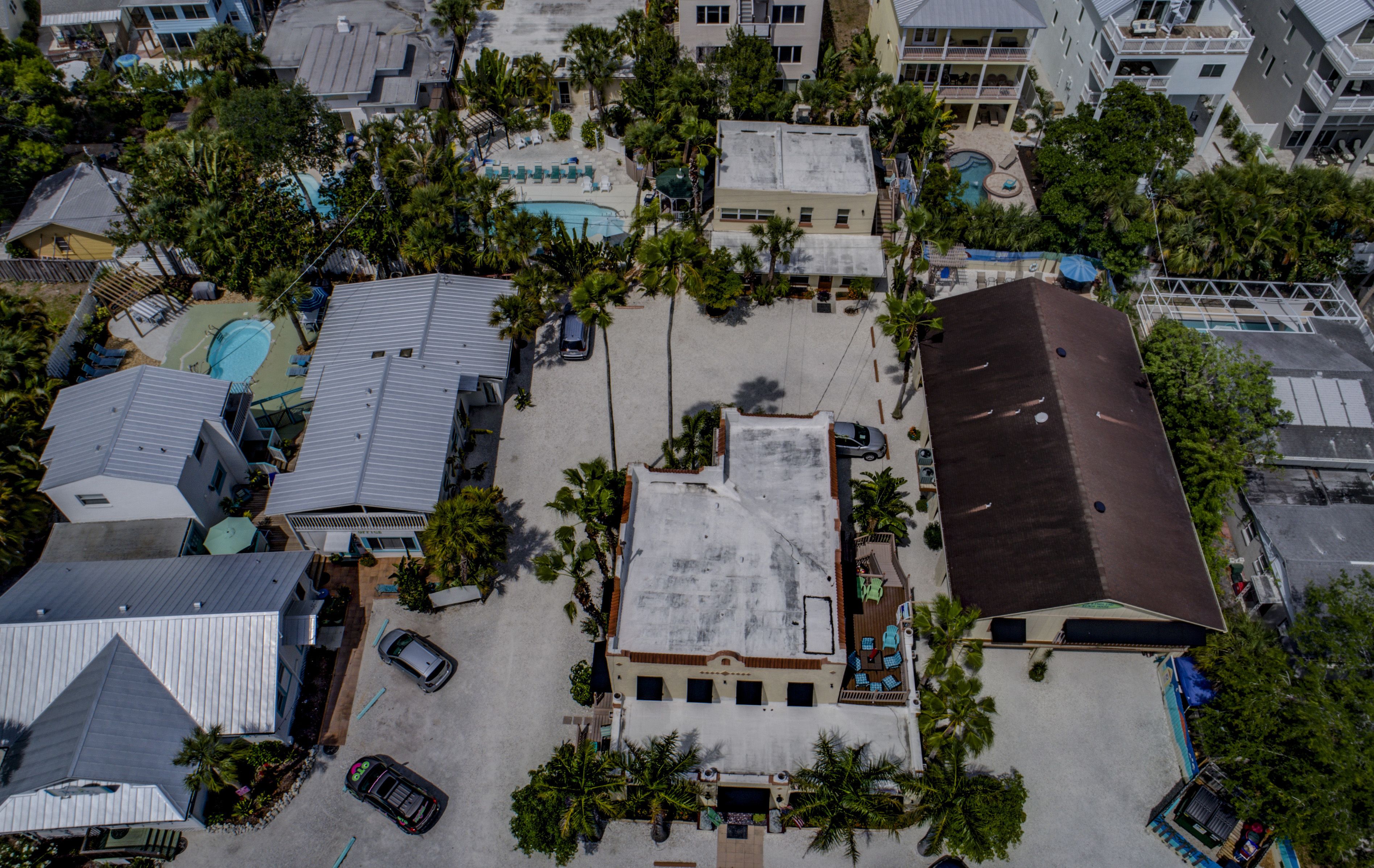 Vista aérea de una zona residencial con varios edificios, una piscina y varios coches estacionados.