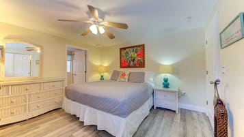 A bedroom with a bed, nightstands, a ceiling fan, a mirror, and a painting.