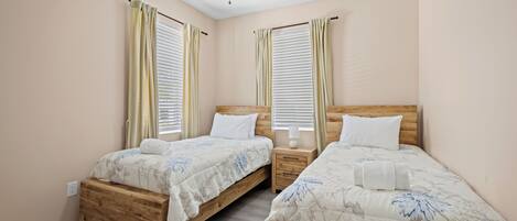 A bedroom with two wooden beds, a ceiling fan, and a nightstand with a lamp.