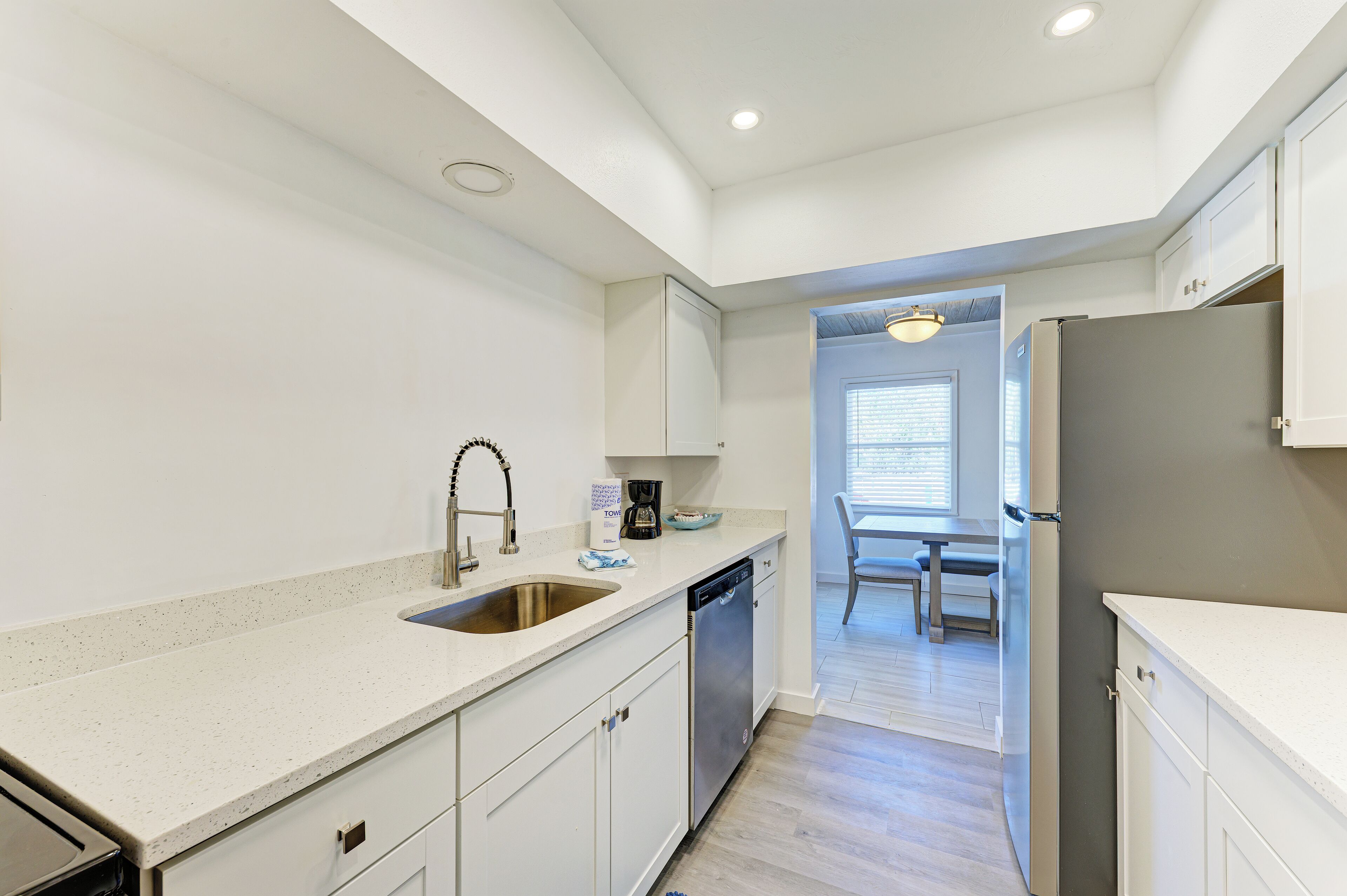 A modern kitchen with white cabinetry, stainless steel appliances, and a light-colored countertop.