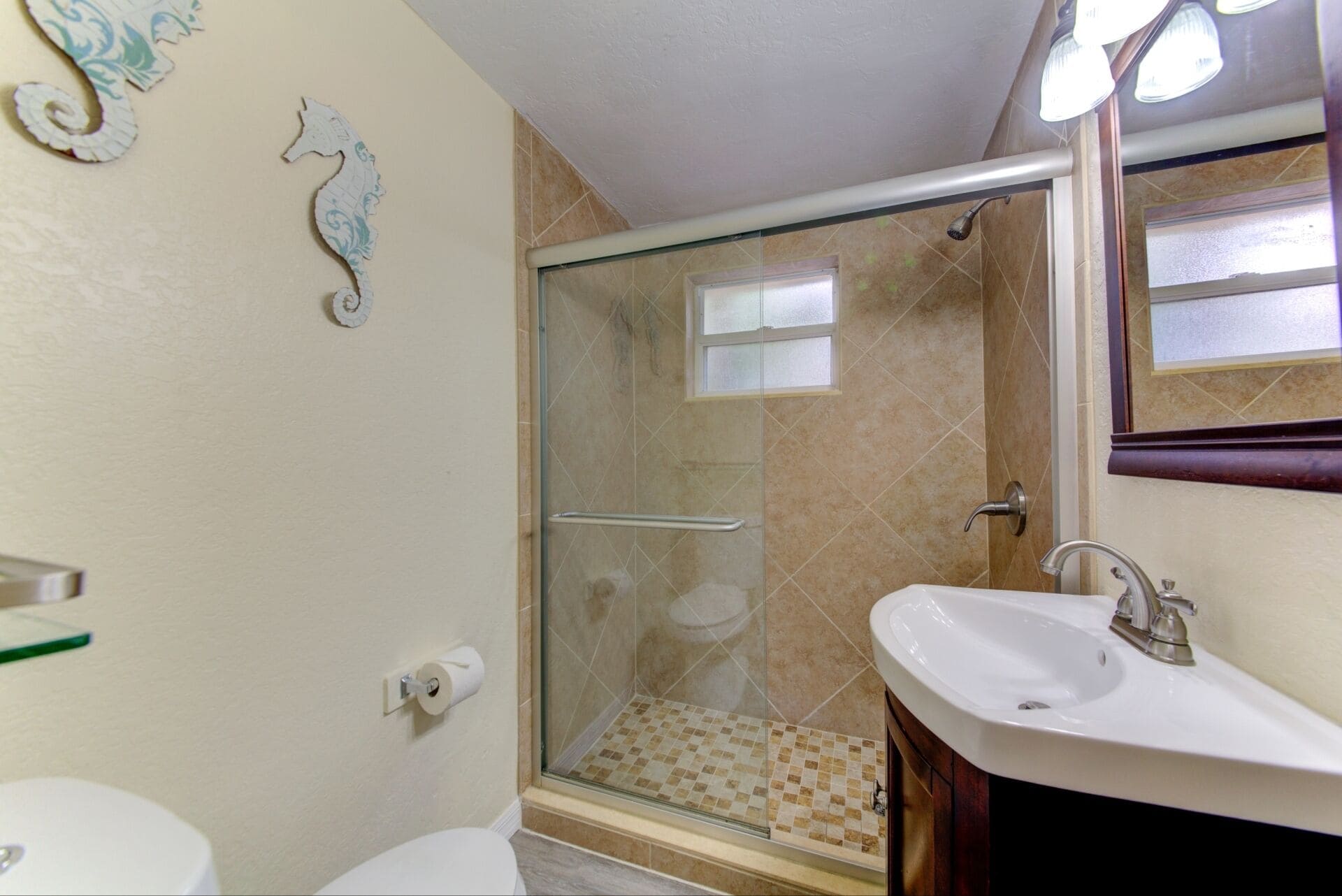 A bathroom with a glass-enclosed shower, a white sink, and a toilet.