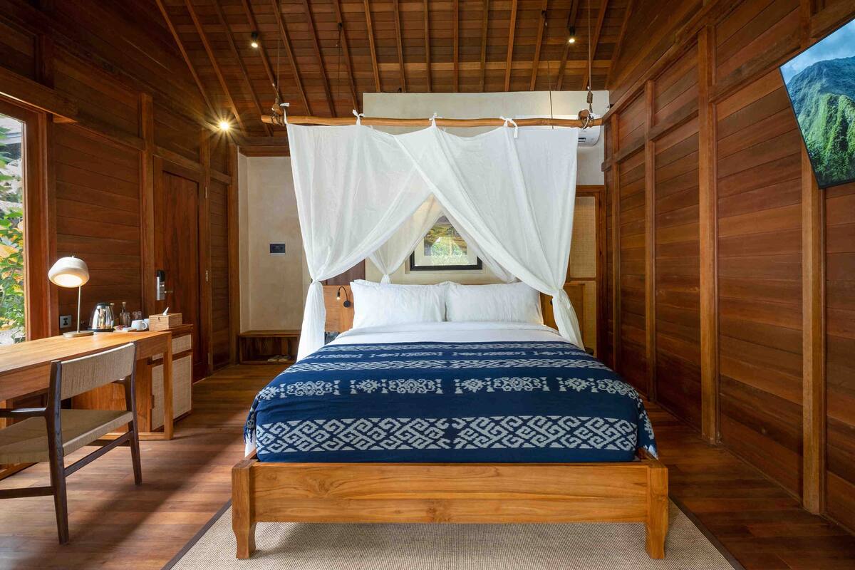 A wooden room with a bed, a desk, and a chair.