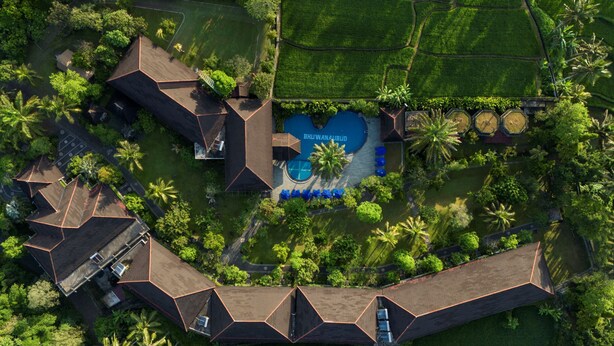 An aerial view of a resort with multiple buildings, a swimming pool, and surrounding lush greenery. - Bhuwana Ubud Hotel and Farm (Ubud)