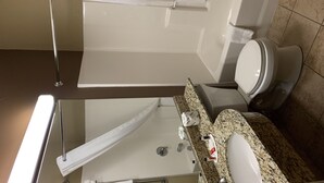 A bathroom with a toilet, sink, and shower area.