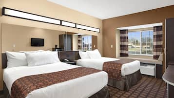 A hotel room with two beds, a TV, a desk, and a window with curtains.