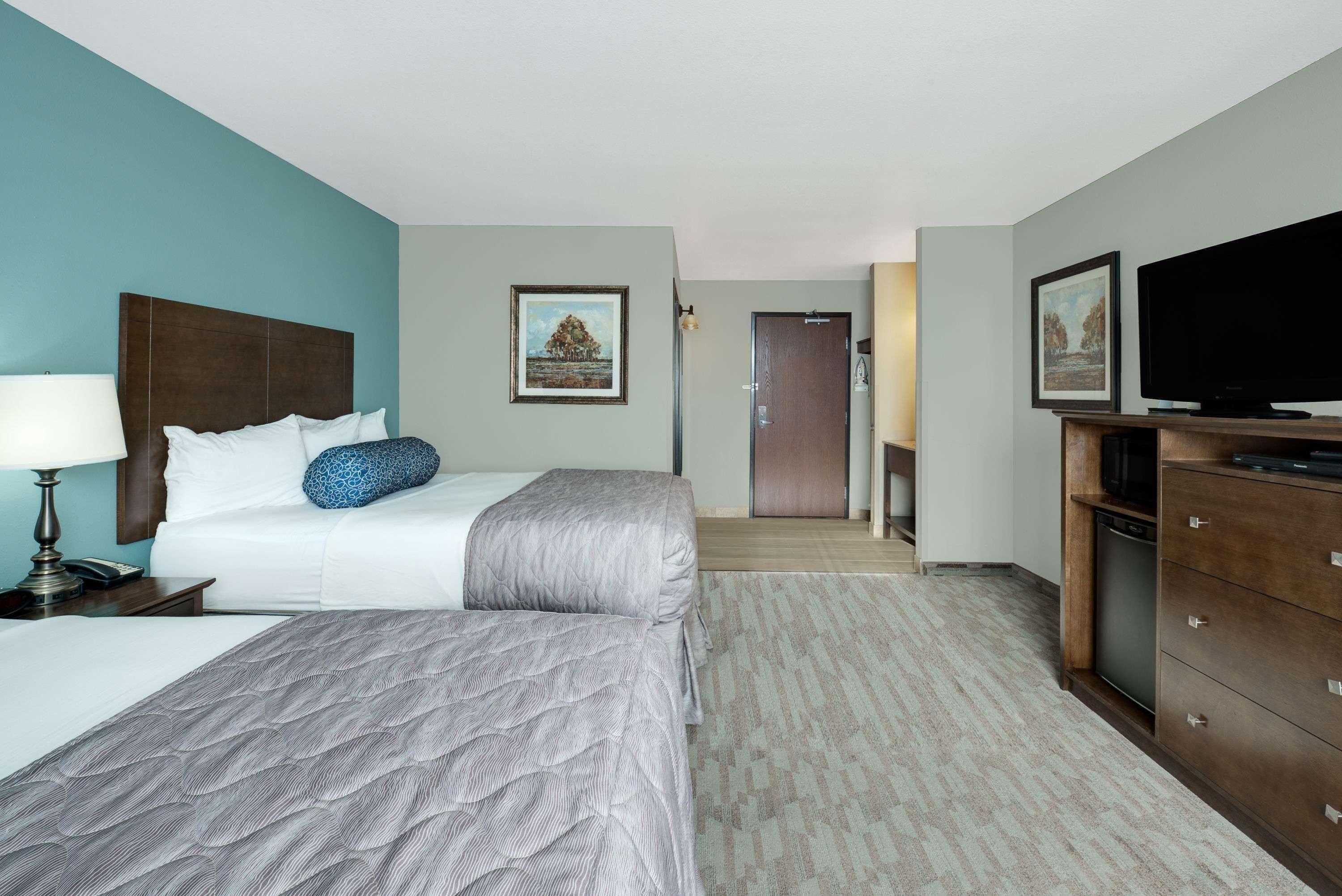 Une chambre d’hôtel équipée d’un lit, d’une télévision, d’un bureau et d’une porte donnant sur un couloir.