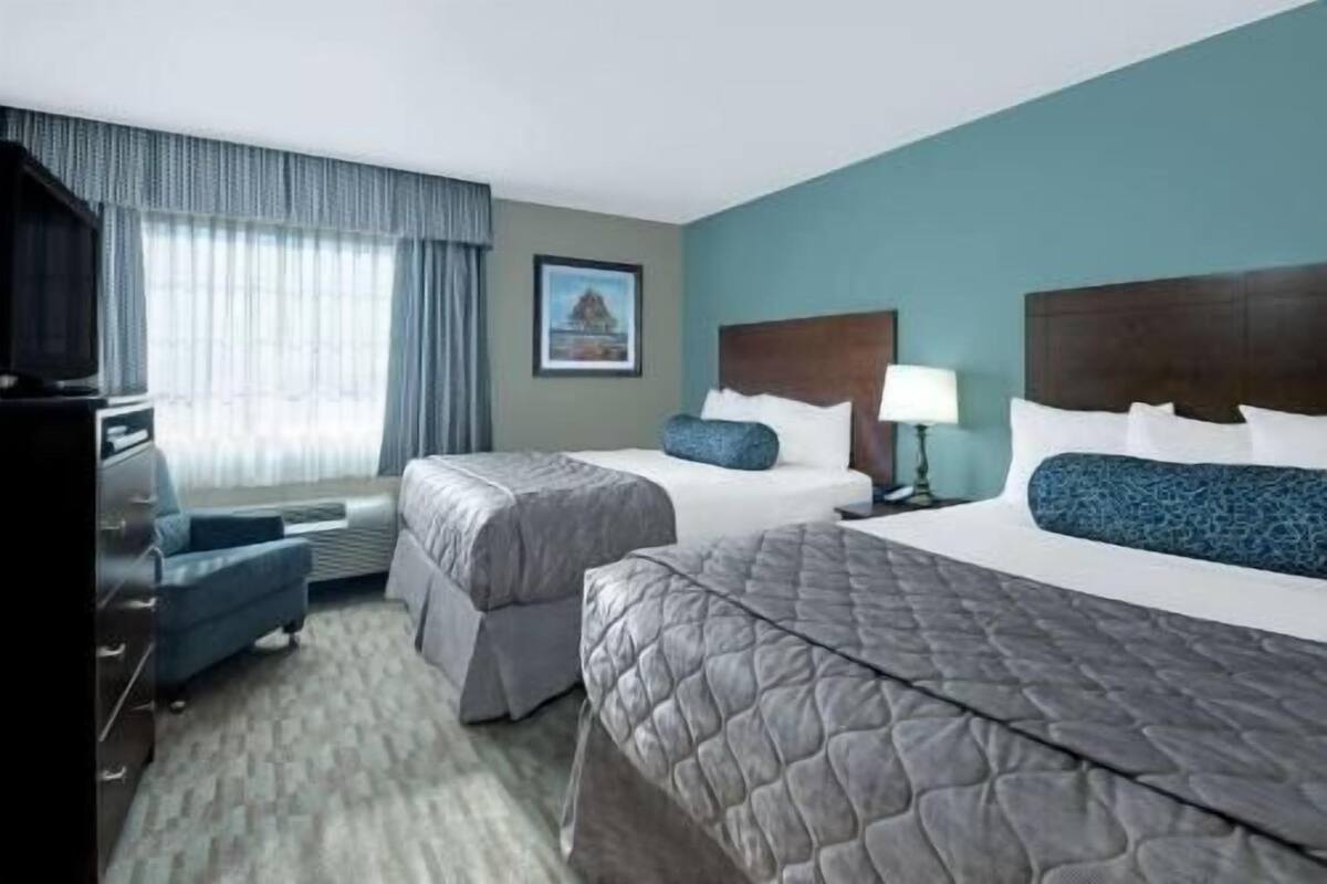 Een hotelkamer met twee bedden, een bureau, een stoel en een televisie.