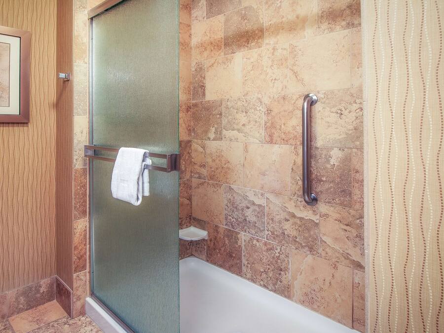 Une salle de bain avec une porte de douche en verre, une baignoire blanche et un porte-serviettes.