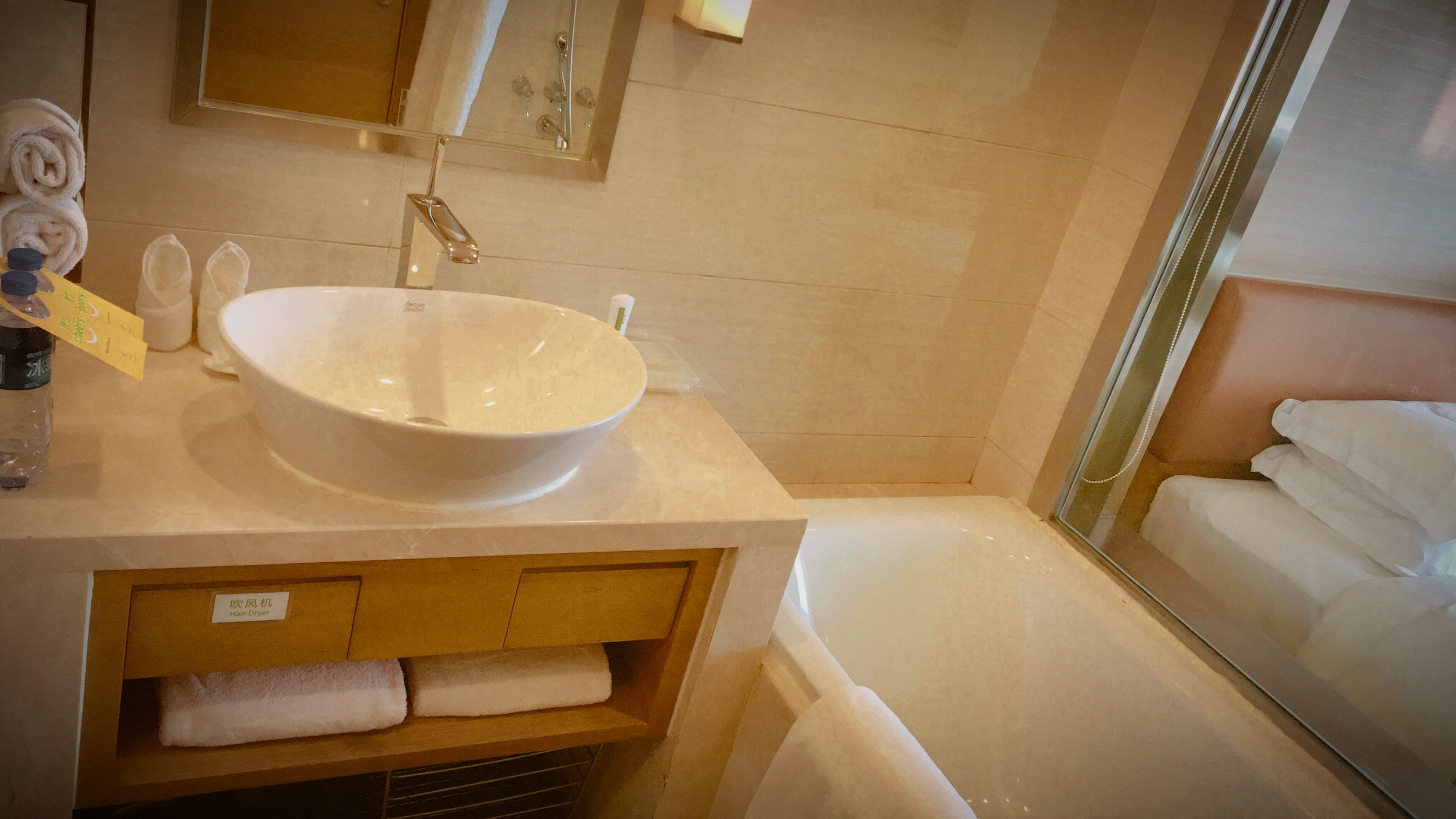 Un baño con un lavamanos grande de color blanco, un espejo, un perchero para toallas y una zona de ducha.