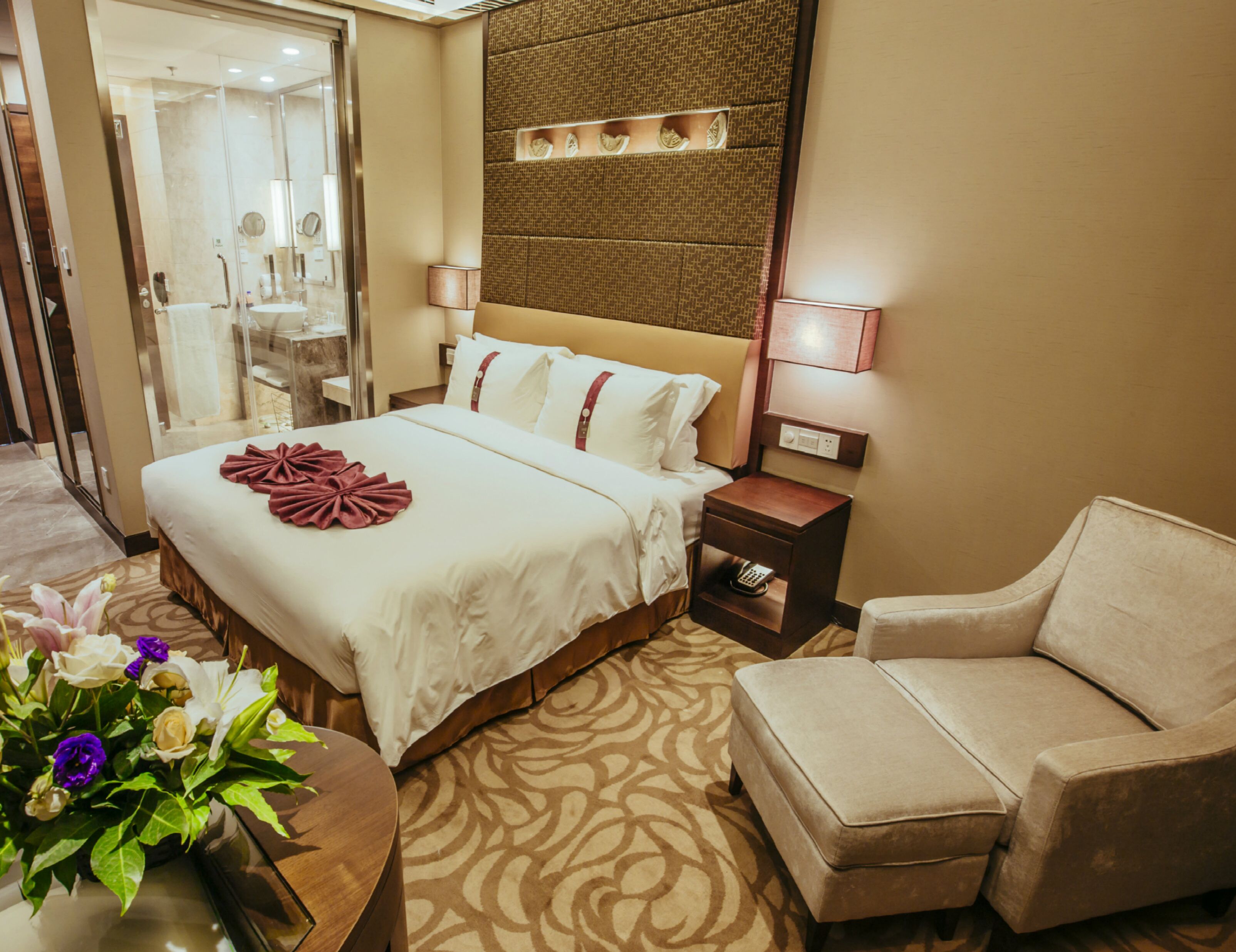 Habitación de hotel con una cama grande, mesita de noche, lámpara y una silla.