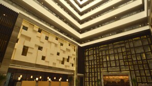 A modern hotel lobby with a central reception desk, multiple floors, and a large glass facade. - Holiday Inn Xi'an Big Goose Pagoda by IHG (Xi'an)