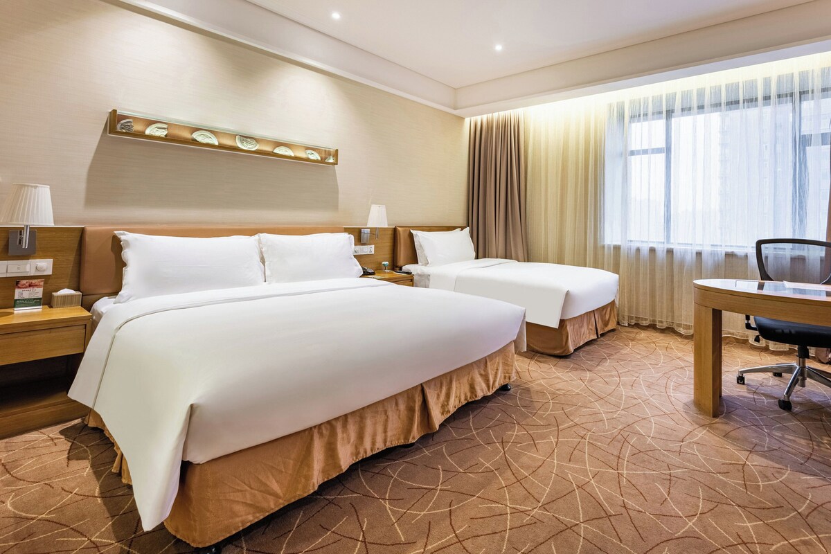 A hotel room with two beds, a desk, and a chair.