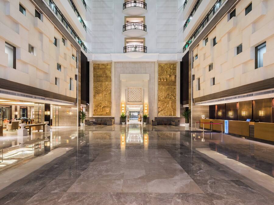 A spacious lobby with a marble floor, a reception desk, and a seating area.