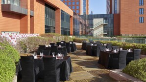 An outdoor dining area with tables and chairs, surrounded by modern buildings and a clear sky. - Holiday Inn Xi'an Big Goose Pagoda by IHG (Xi'an)