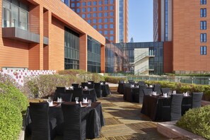 An outdoor dining area with tables and chairs, surrounded by modern buildings and a clear sky. - Holiday Inn Xi'an Big Goose Pagoda by IHG (Xi'an)