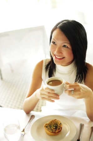 A person sitting at a table with a plate of food and a cup of coffee. - Holiday Inn Xi'an Big Goose Pagoda by IHG (Xi'an)