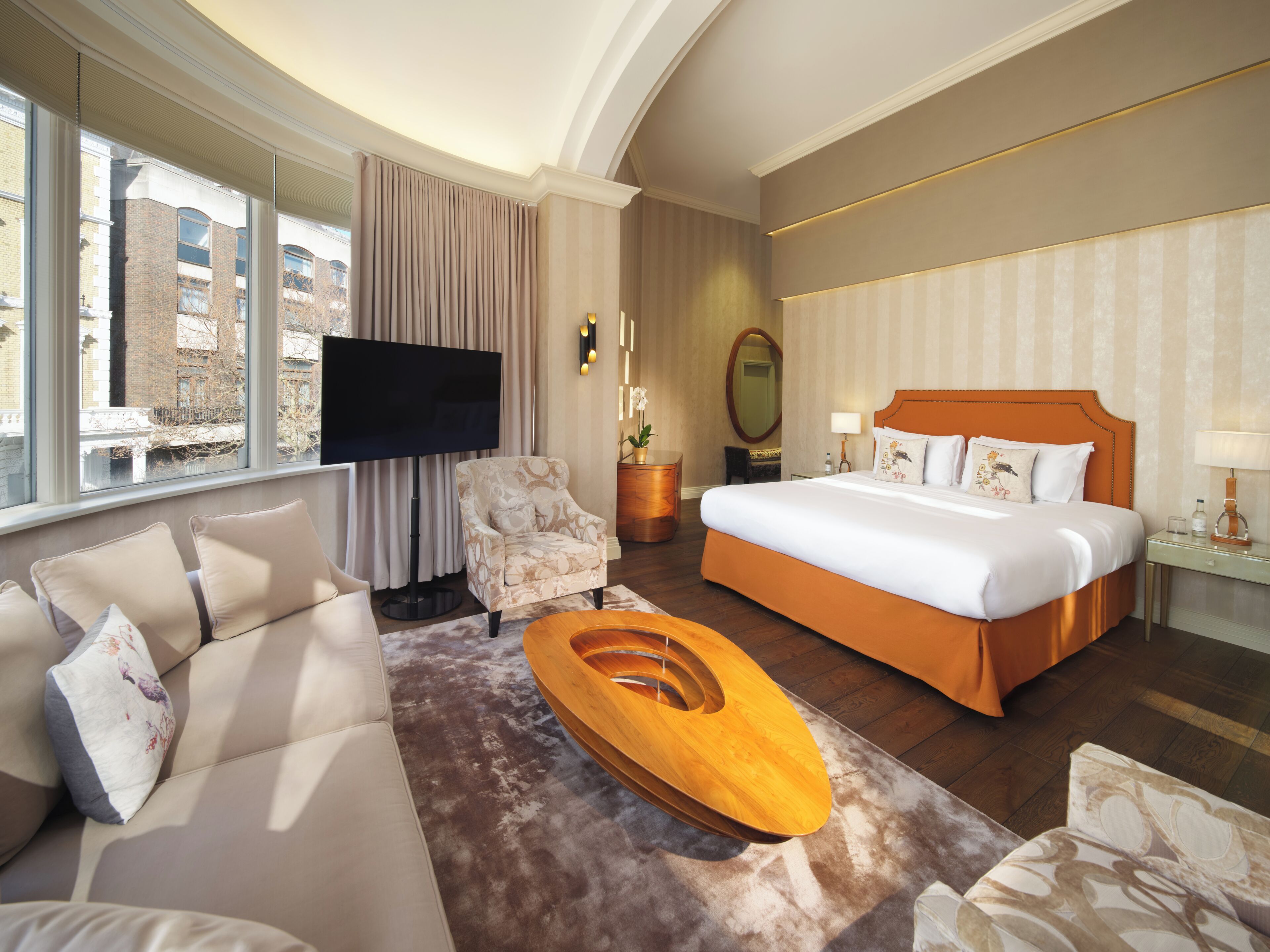 Habitación de hotel con una cama grande, un sofá, una televisión y vistas a la ciudad.