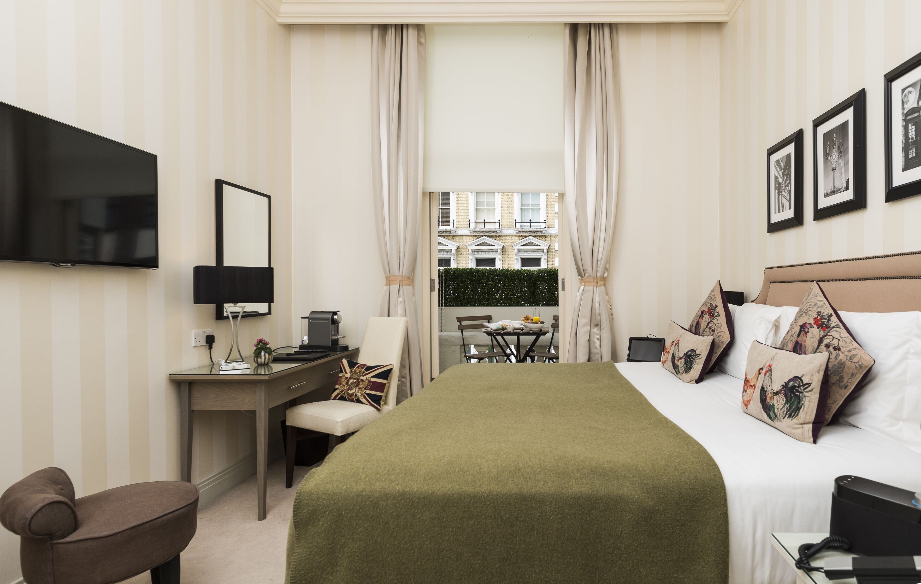 Een hotelkamer met een bed, een bureau met een computer, een stoel, een televisie en een raam met gordijnen.