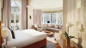 Une chambre d’hôtel avec un grand lit, un canapé, une table basse, une lampe, une plante et une vue sur la ville.