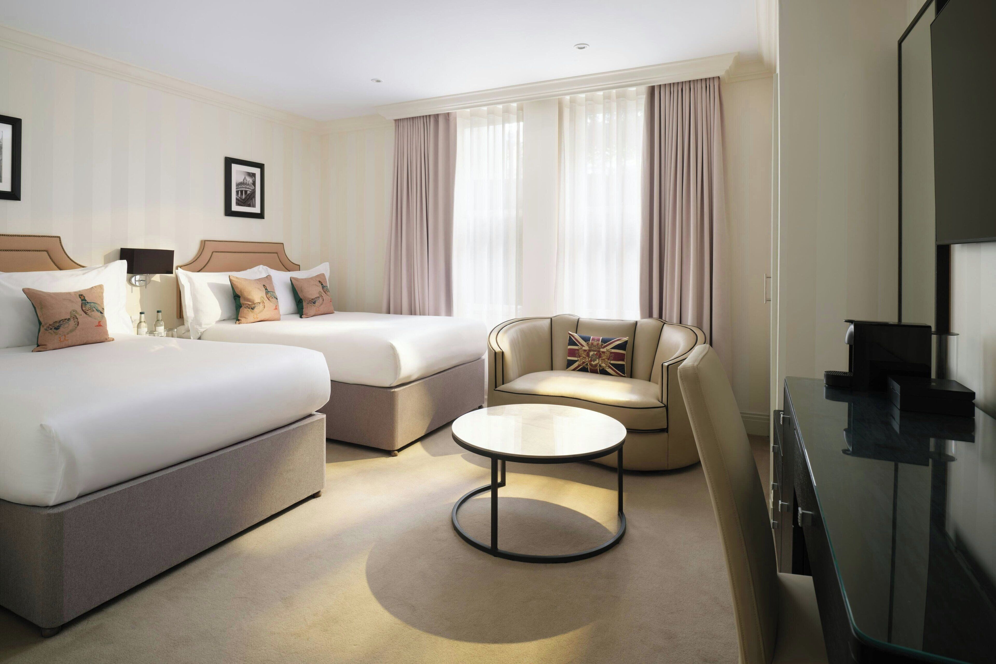 Een hotelkamer met twee bedden, een bank, een ronde salontafel en een televisie.