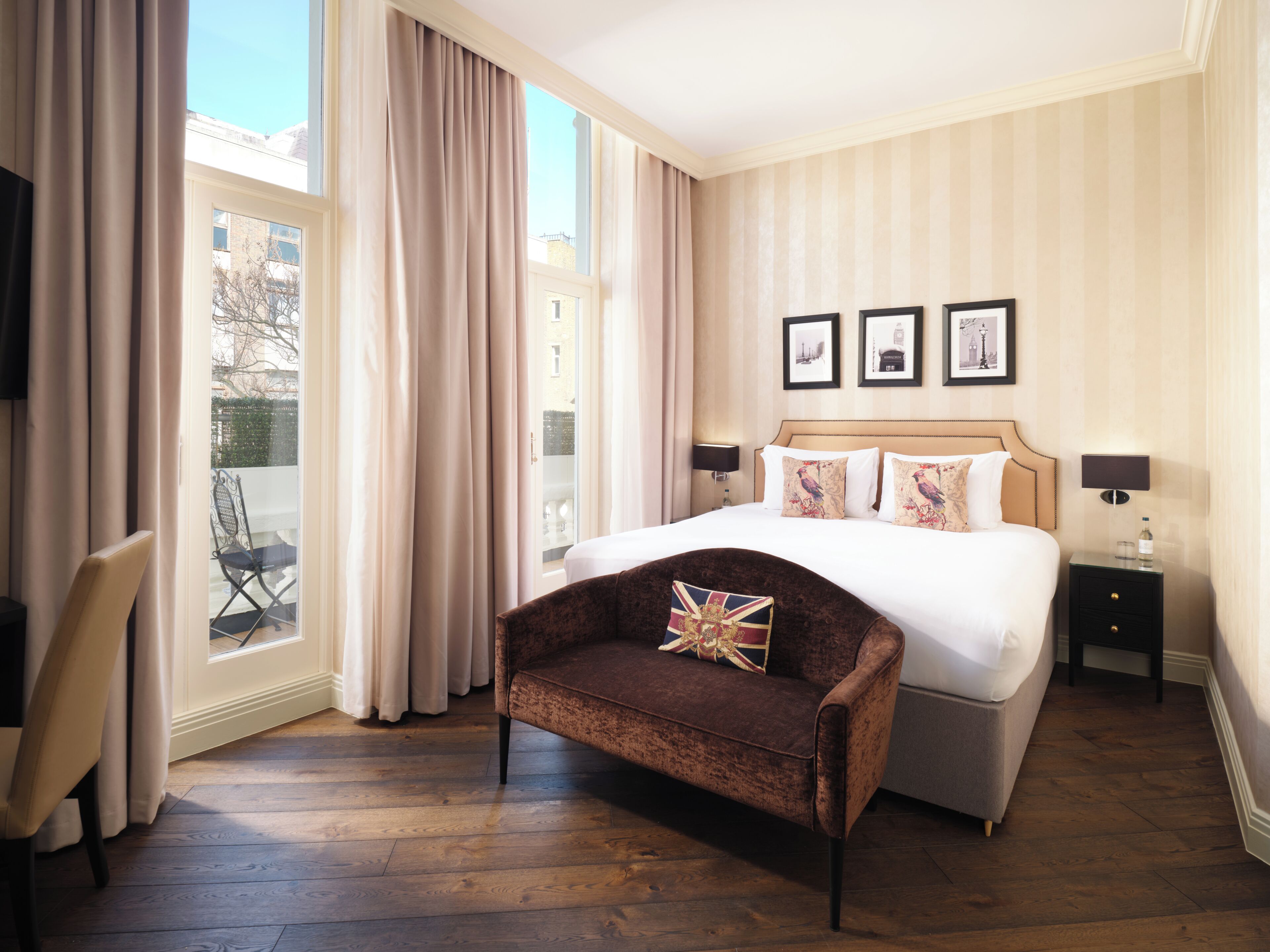 Une chambre d’hôtel avec un grand lit, un coin salon avec un fauteuil, une petite table et une vue sur l’extérieur.