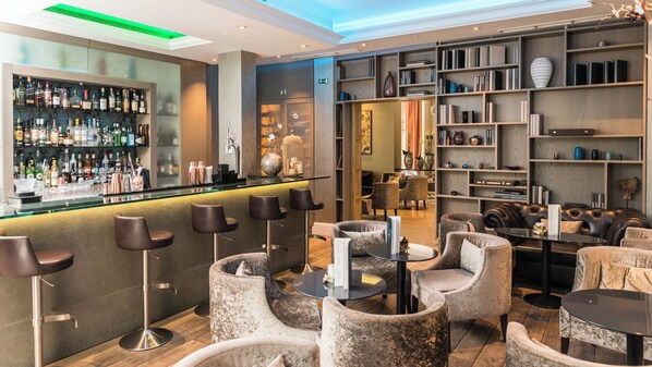 A bar area with stools, a bar counter, and shelves with bottles. There are seating areas with chairs and tables. - Hotel Xenia, Autograph Collection (London)