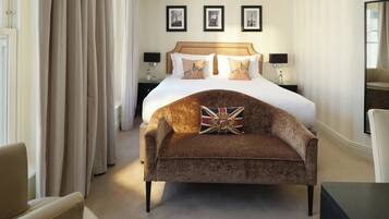 A hotel room with a large bed, a sofa, a nightstand, and a mirror.