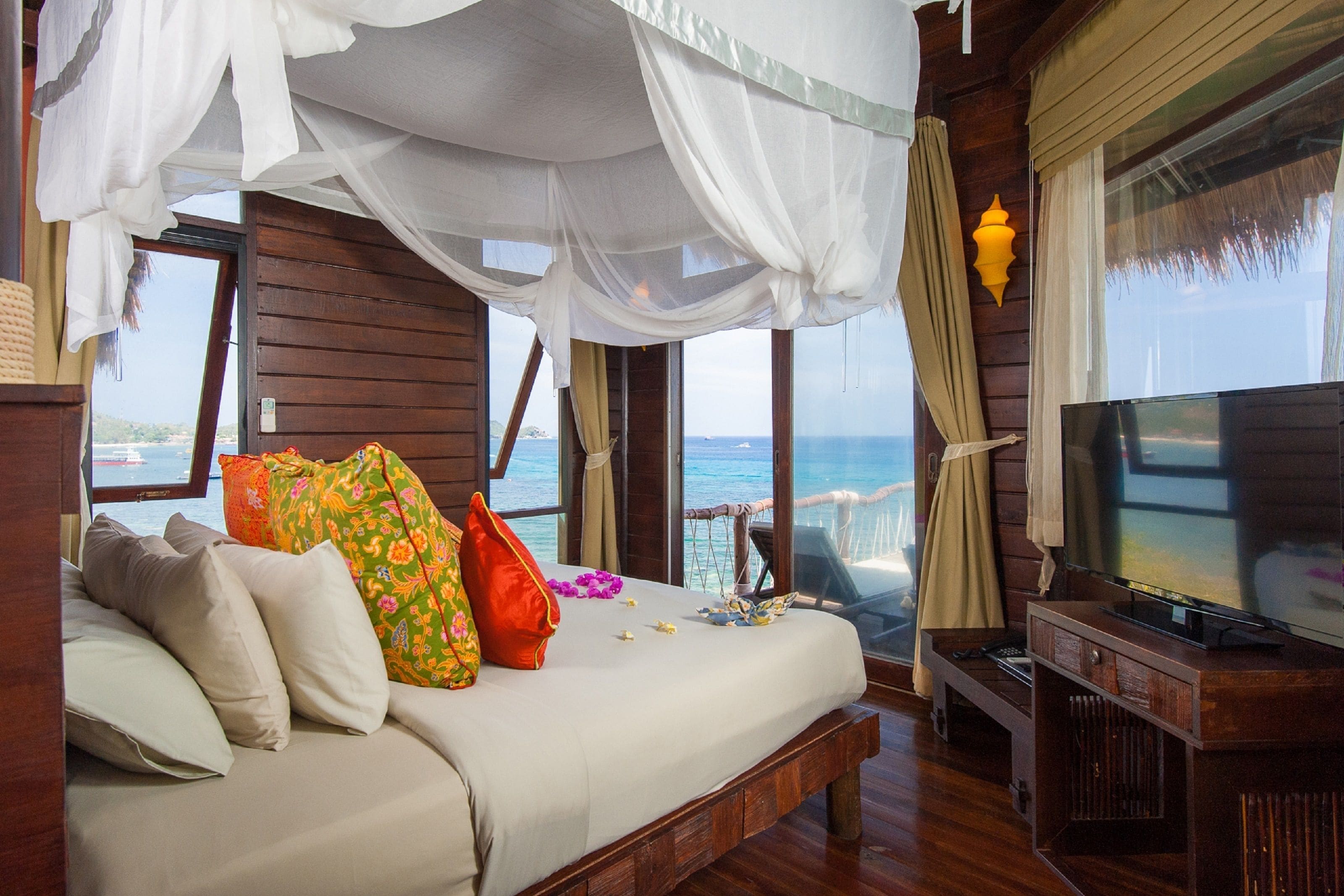 Un dormitorio con cama, televisor y vista al océano.
