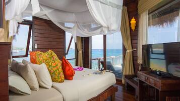 Un dormitorio con cama, televisor y vista al océano.
