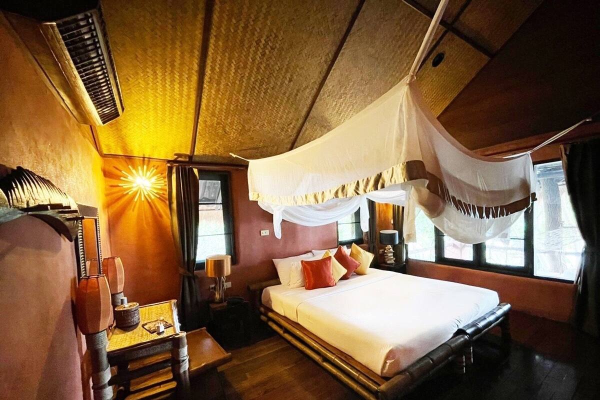 Une chambre avec un lit, une table de chevet, une lampe et une fenêtre avec des rideaux.
