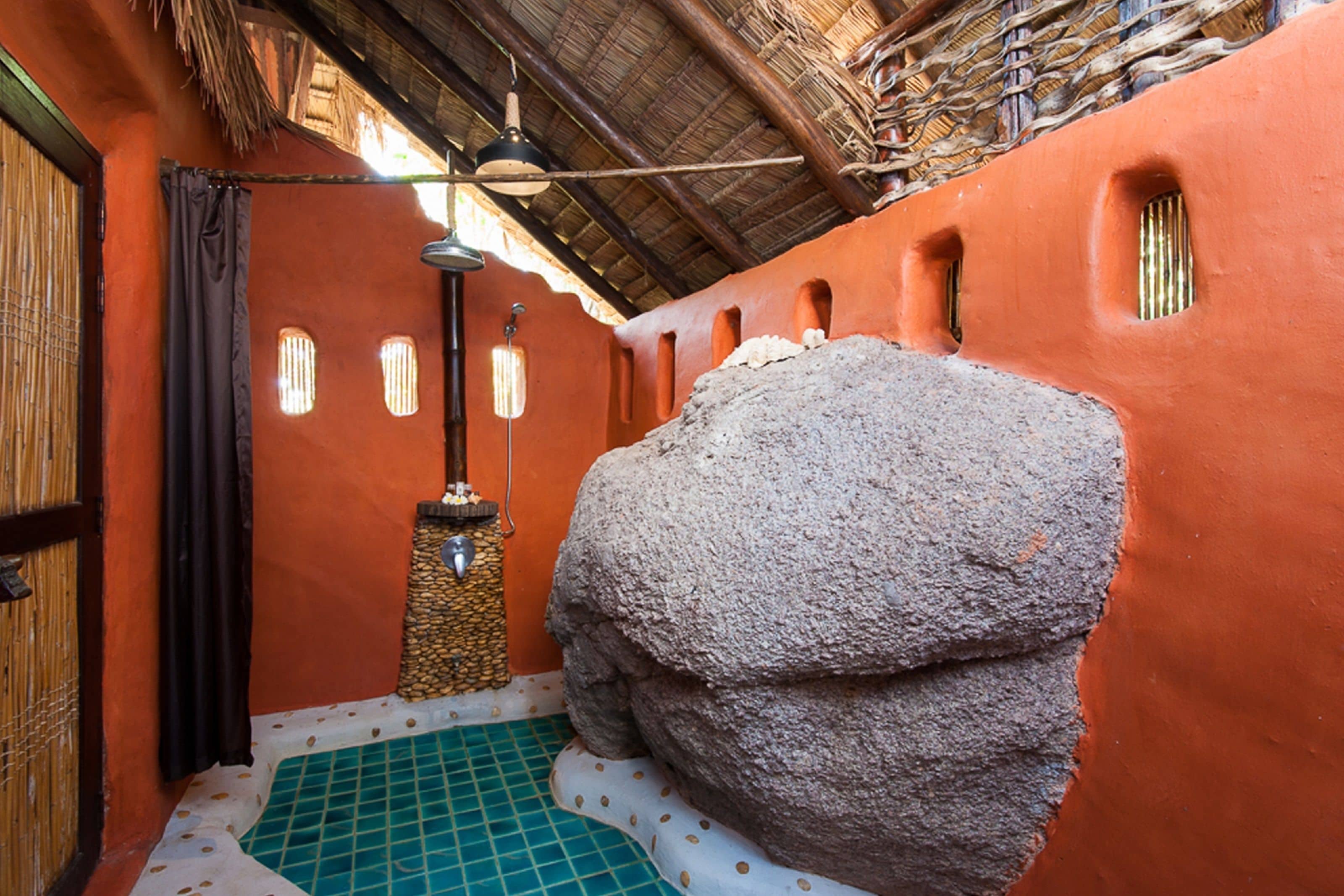 A bathroom with a stone sink, a bamboo shower curtain, and a tiled floor.