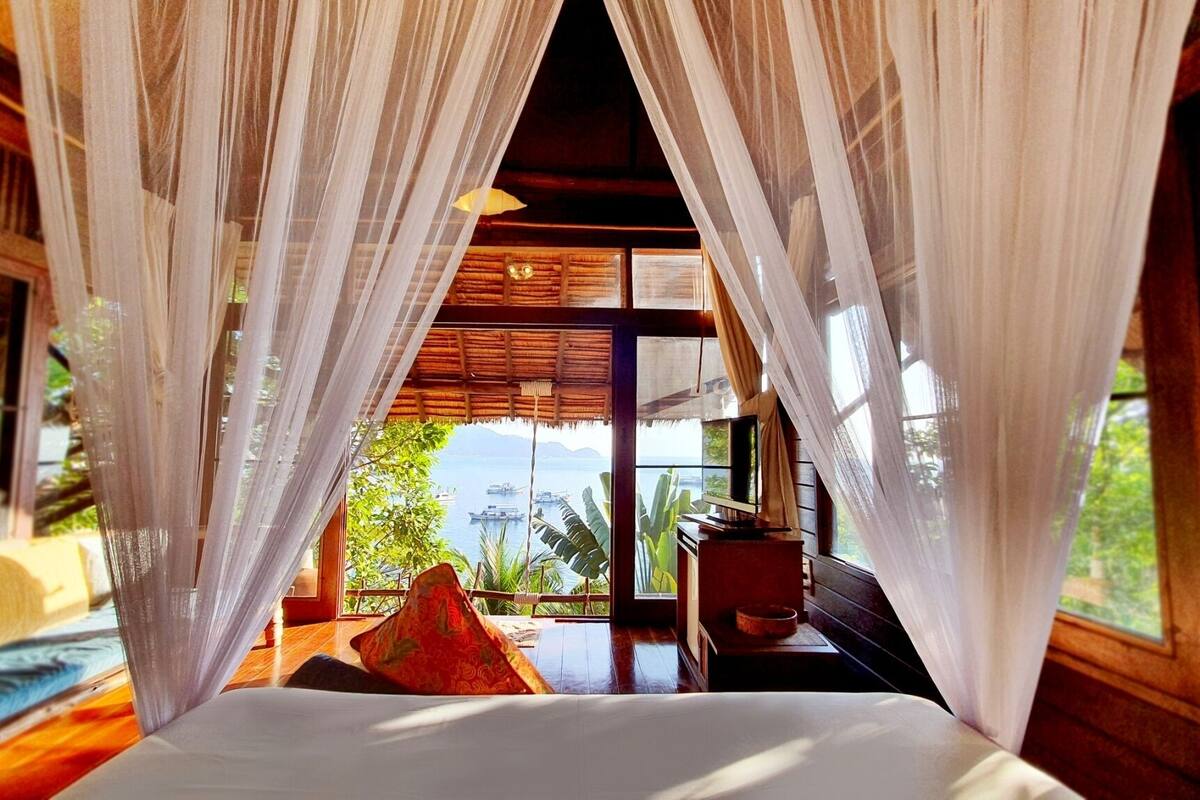 Une chambre avec un lit, un bureau en bois et une vue sur la mer.