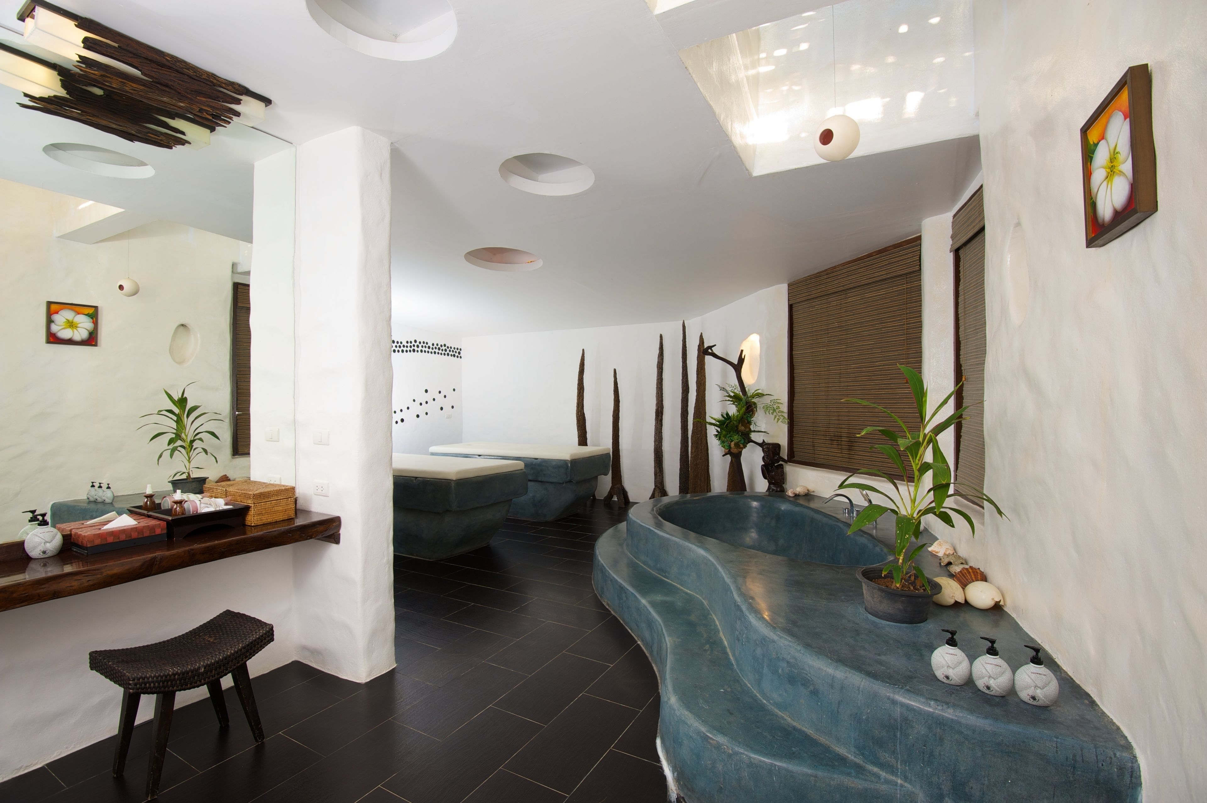 Ein modernes Badezimmer mit einem blauen, gebogenen Waschbecken, einer Holzbank und einem wandmontierten Spiegel.