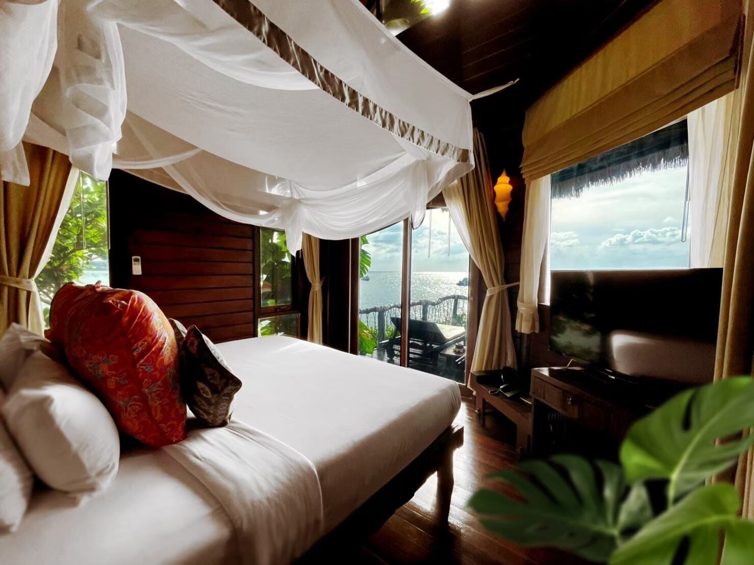 A bedroom with a bed, a TV, and a view of the sea.