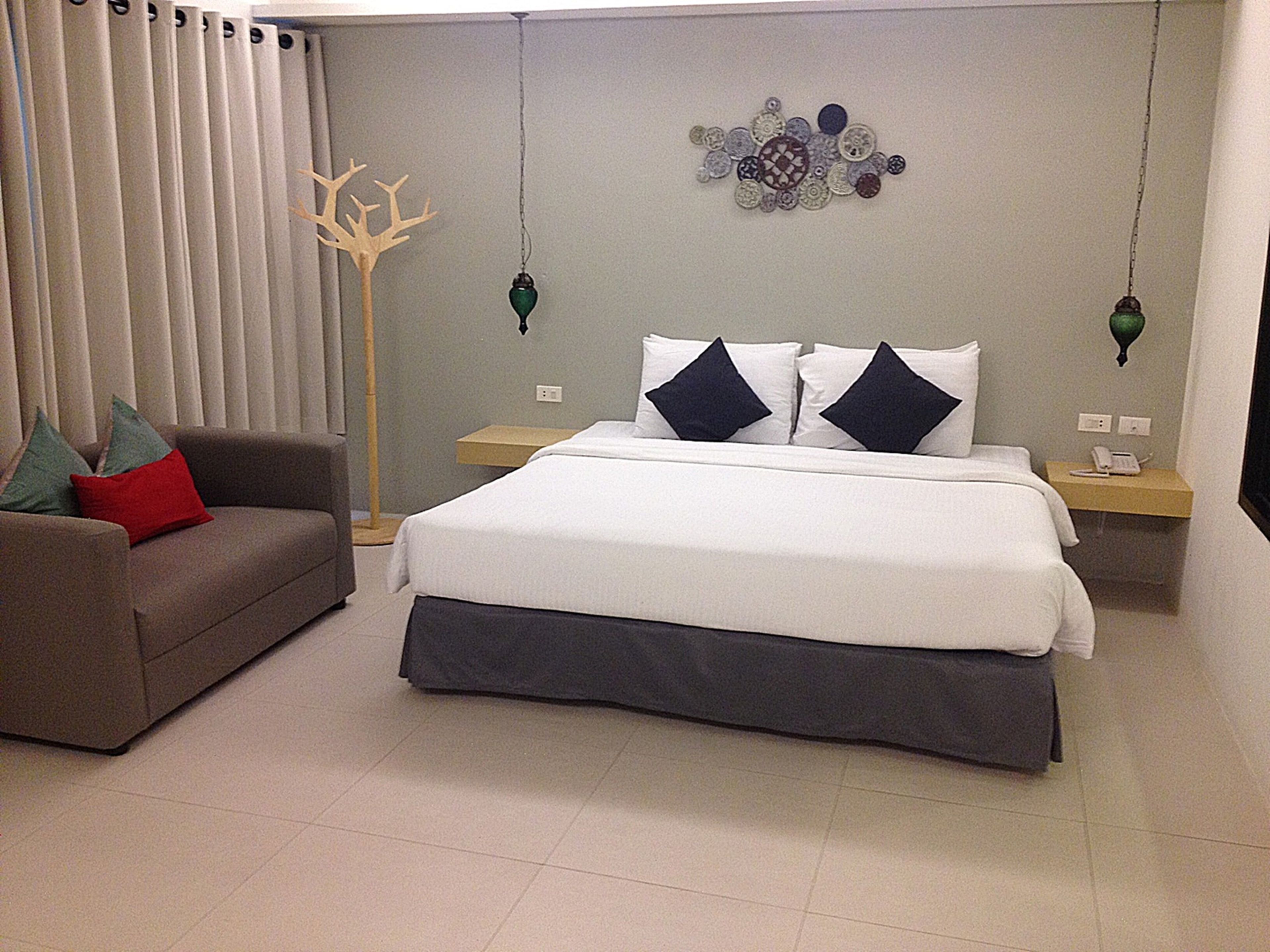 Un dormitorio ordenado con cama, sofá y un adorno en la pared.