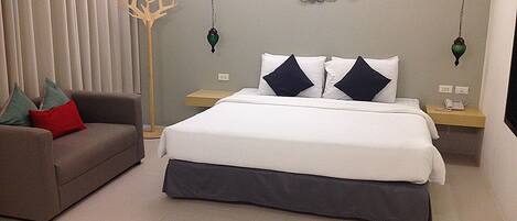Un dormitorio ordenado con cama, sofá y un adorno en la pared.