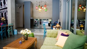 Un hall d’entrée spacieux, avec un canapé vert, une table basse en bois et des lampes colorées suspendues au plafond.