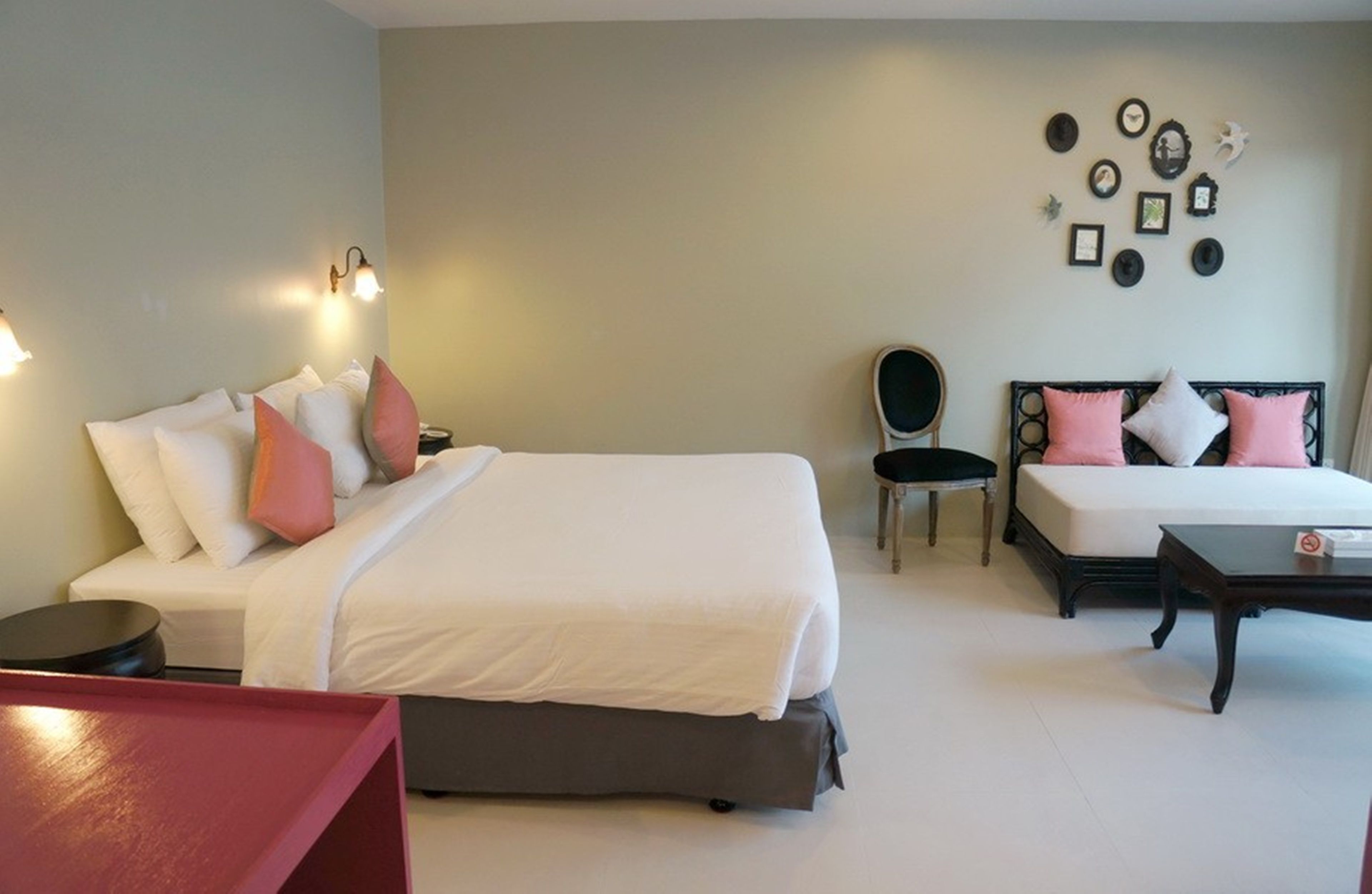 A hotel room with two beds, a chair, a table, and wall decor.