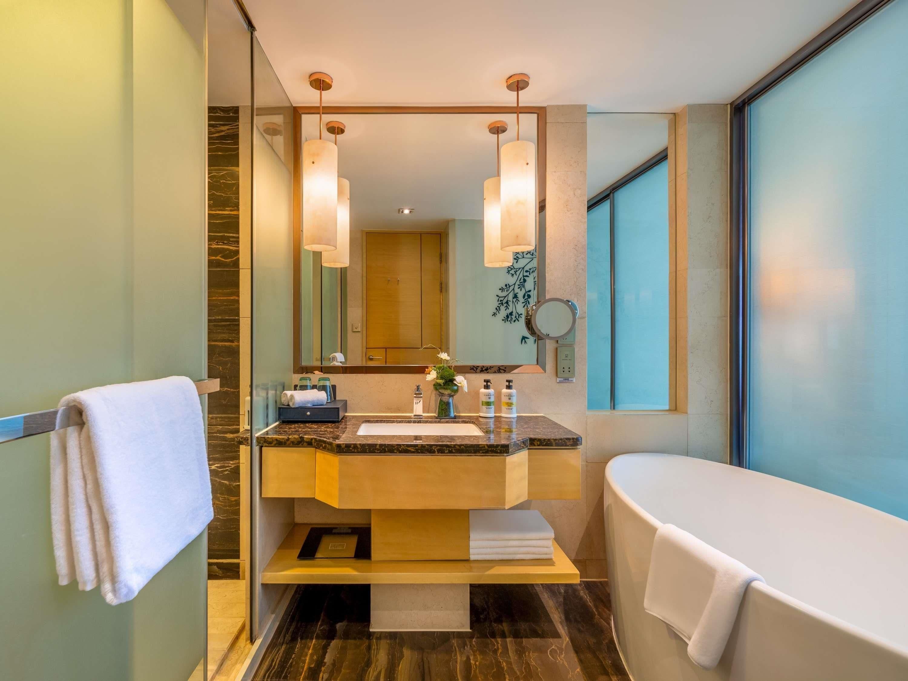 A modern bathroom with a marble sink, a large mirror, and a bathtub.