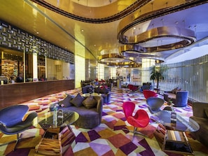 Eine moderne Hotellobby mit einem geometrisch gemusterten Boden, runden Tischen und zeitgenössischer Sitzmöbel.