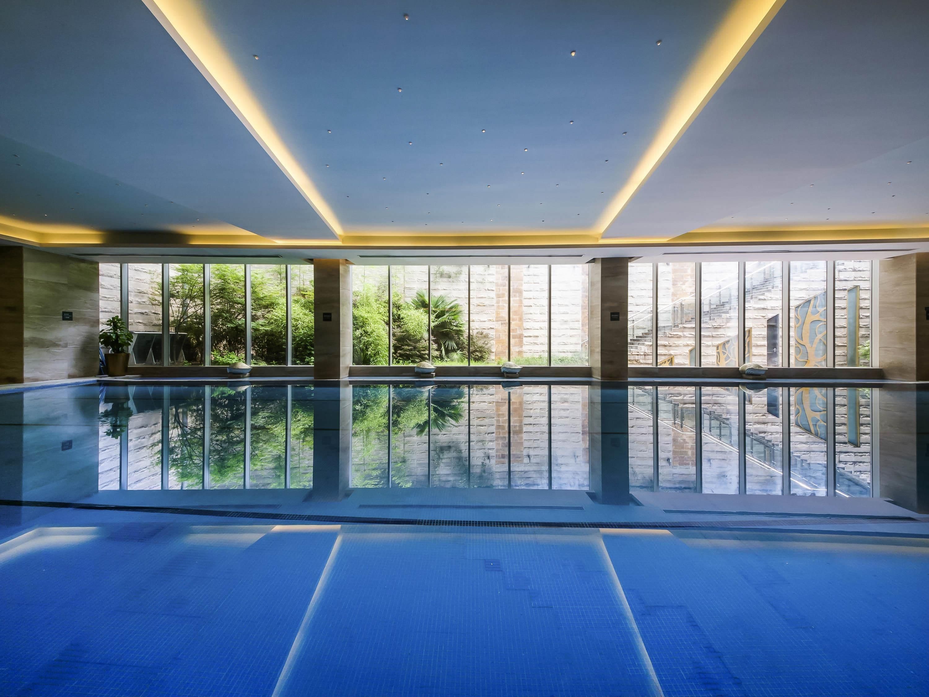 A large indoor swimming pool with clear glass walls, allowing views of the outdoors.