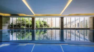 A large indoor swimming pool with clear glass walls, allowing views of the outdoors.