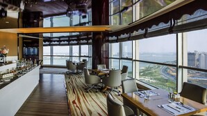A modern hotel lobby with a bar, seating area, and large windows offering a city view. - Pullman Linyi Lushang (Linyi)